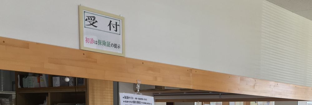 受付カウンター。「初診は保険証の提示」の案内